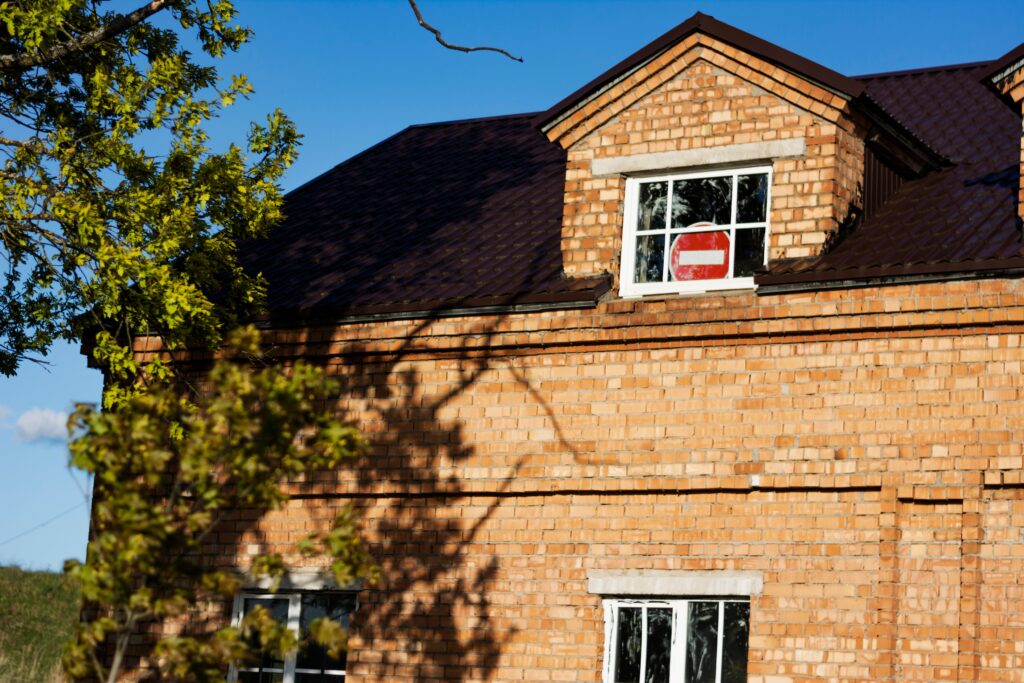 Close-up of a red brick house exterior featuring a no entry sign in a window.