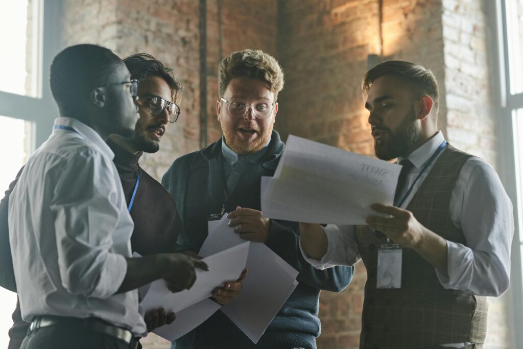 Group of colleagues discussing documents in an industrial-style office.