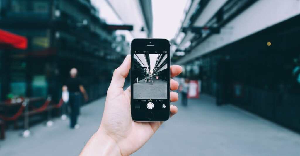 Close-up of a hand holding a smartphone capturing an urban street view. Modern digital photography concept.