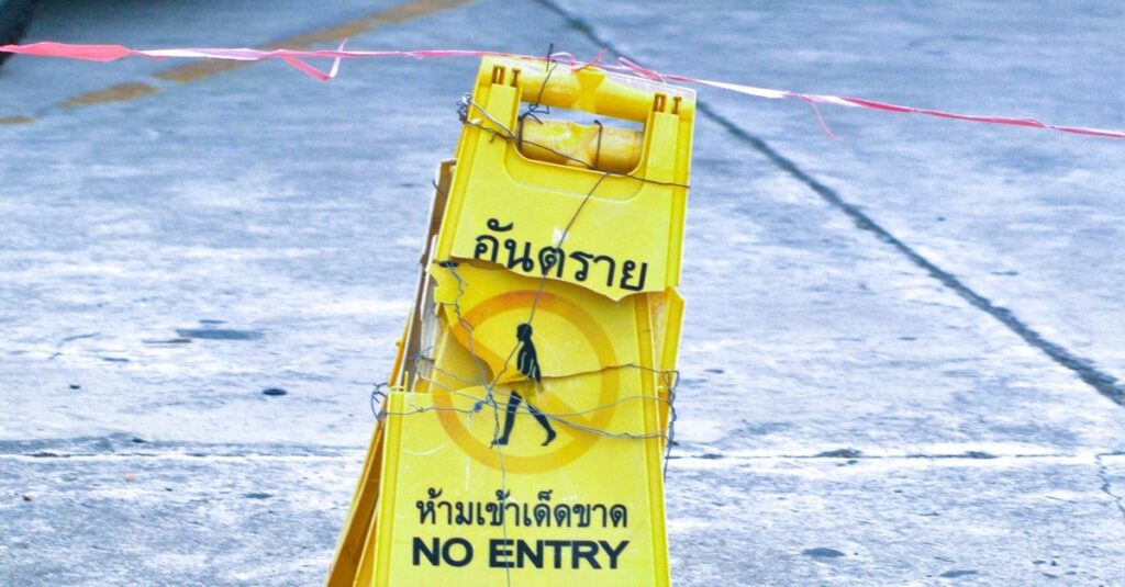 Bright yellow no entry sign on a city pavement, indicating a restricted area.