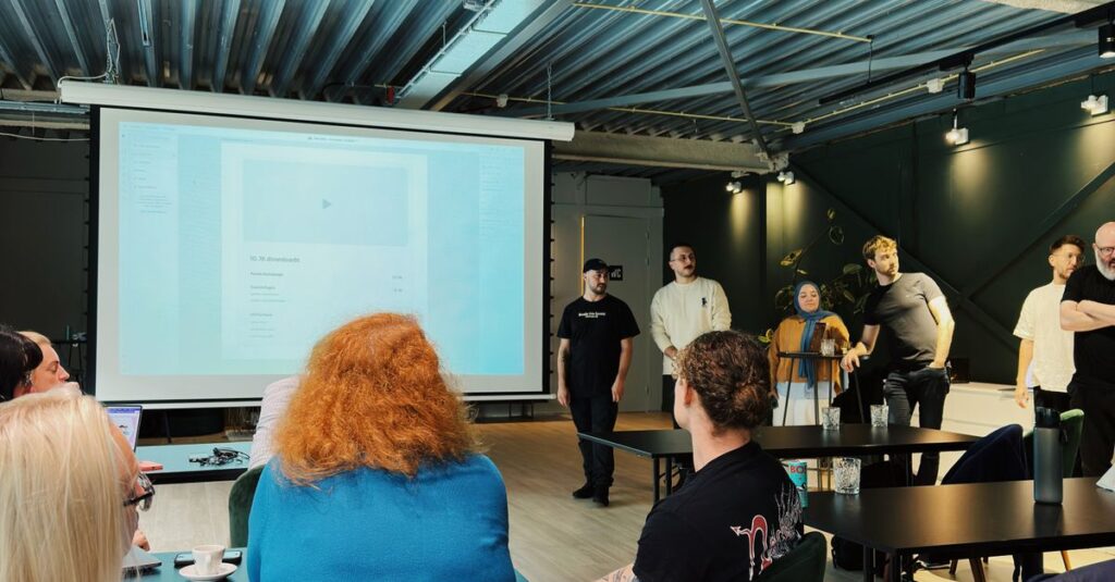 A group of people attending a presentation in an industrial-style office in Amsterdam.
