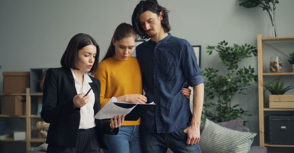 A couple reviewing documents with a real estate agent indoors.