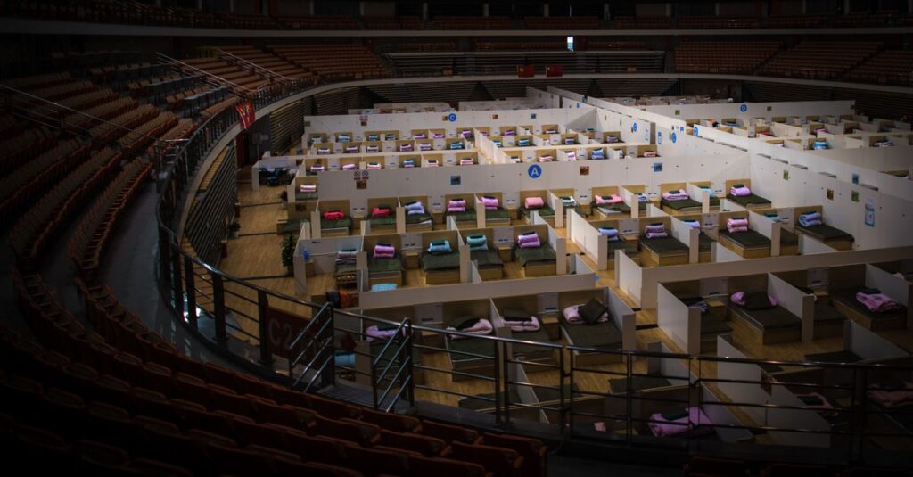 Interior view of a temporary healthcare facility inside a converted stadium with beds prepared for patients.