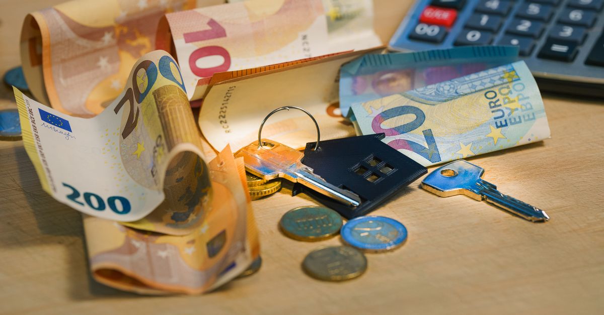 Euro banknotes and coins with house keys on a table symbolize finance and real estate.