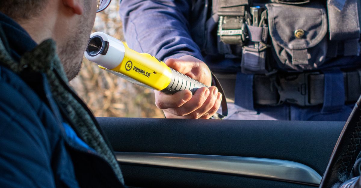 A police officer administering a breathalyzer test to a driver during a traffic stop.