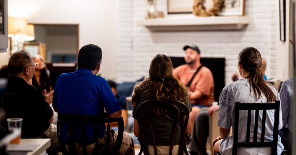 A diverse group engages in a casual conversation in a cozy living room setting.