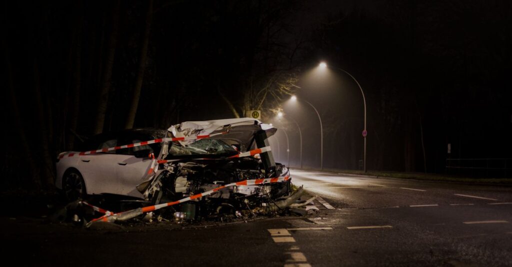 A wrecked car after a crash on a dimly lit street in Berlin at night.