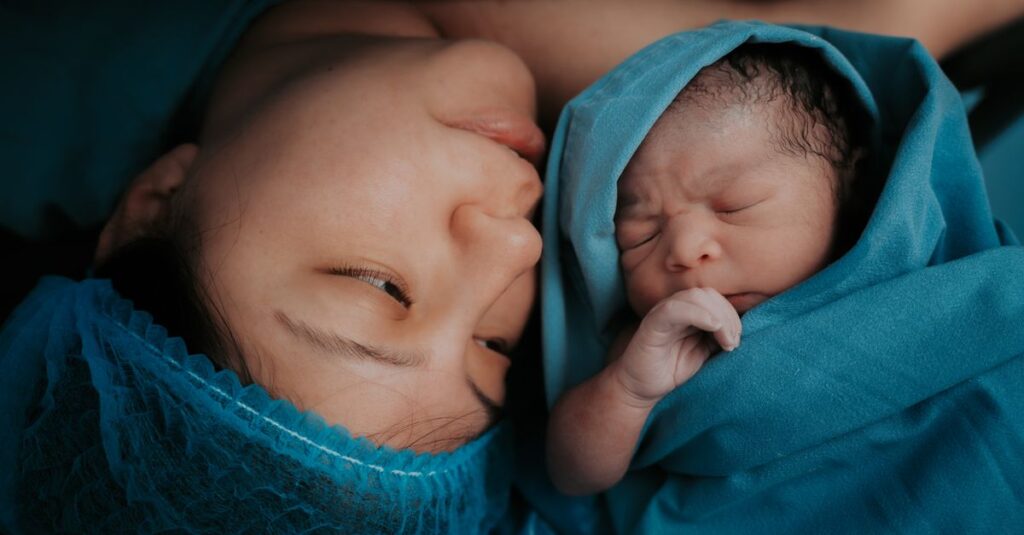 A touching image of a mother and her newborn baby wrapped in blue medical blankets.
