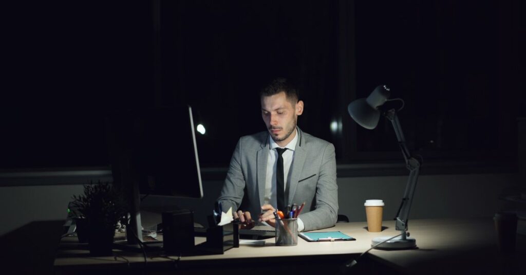 A focused businessman working late in a dimly lit office at night.