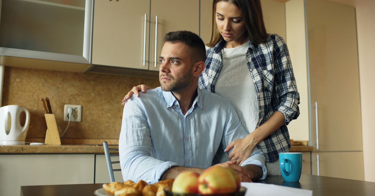A thoughtful couple shares an emotional moment in a cozy kitchen setting.