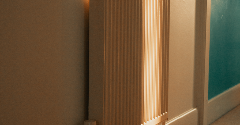 A wall-mounted radiator warmly lit by sunlight in a cozy indoor setting.