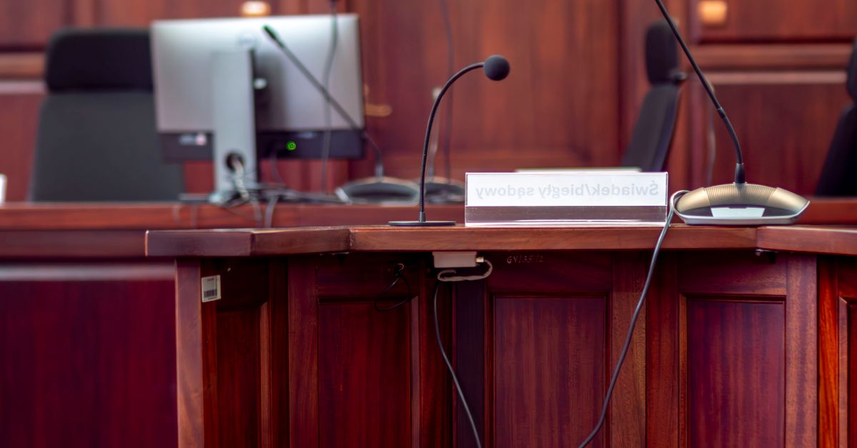Close-up of a wooden podium with microphones in a Polish courtroom setting.