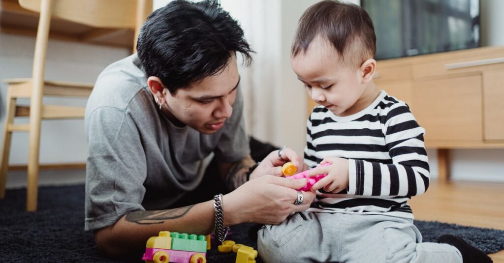 A loving father and his young son bonding while playing with toys on the floor.