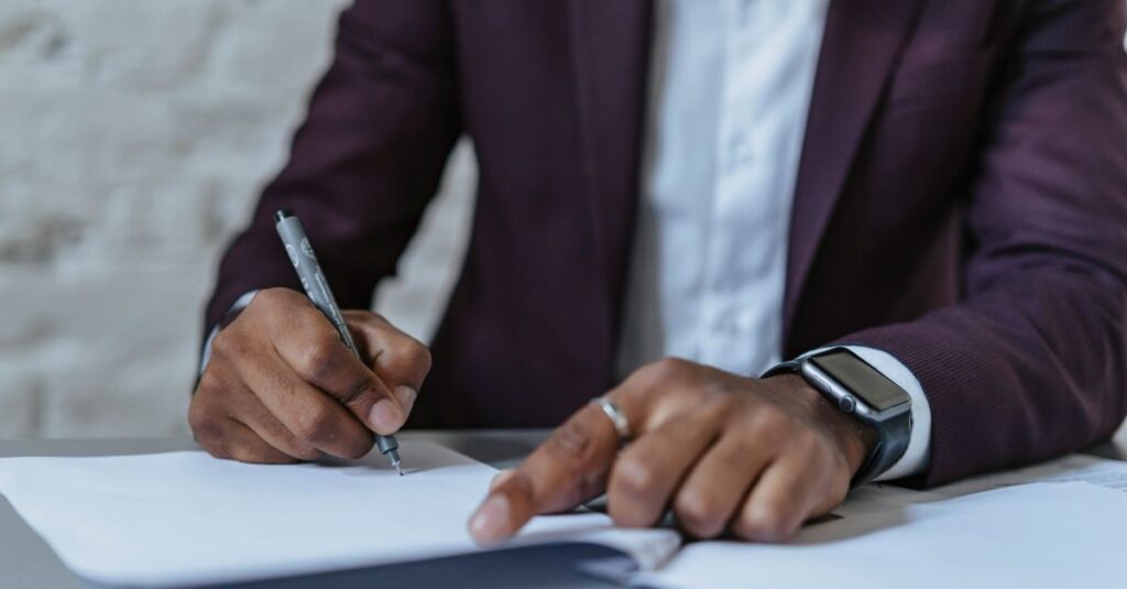Close-up of a man signing documents in an office. Business-focused and professional environment.