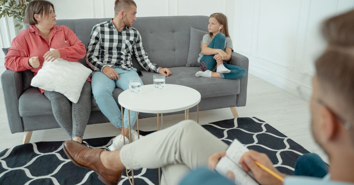 Family therapy session featuring parents and child with therapist in a cozy office setting.