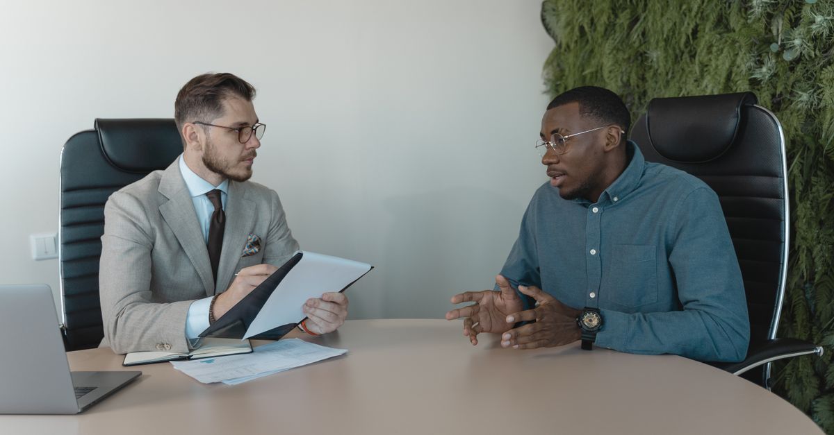 Two businessmen engaged in a discussion during a job interview in a contemporary office environment.