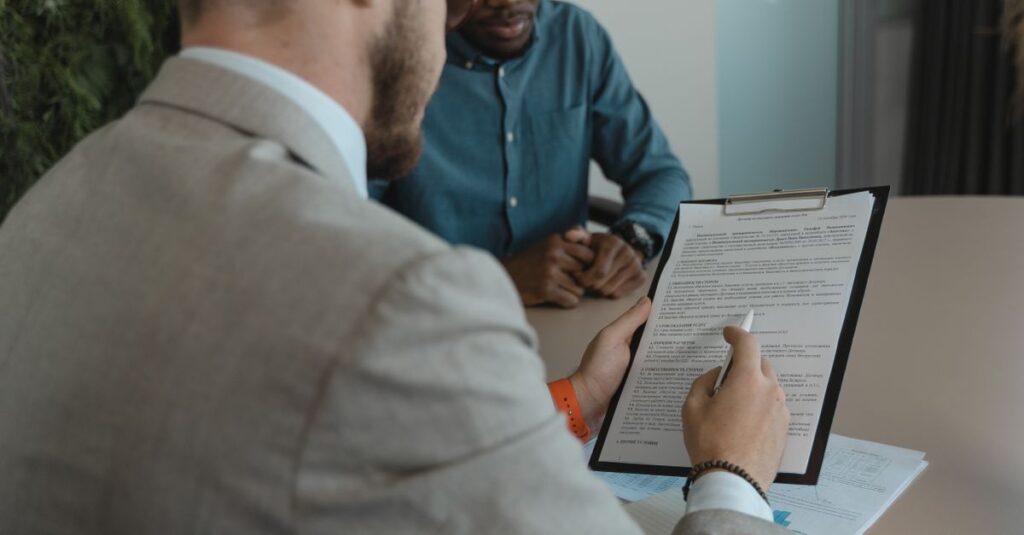 A recruiter reviews a candidate's documents during a job interview in a modern office setting.