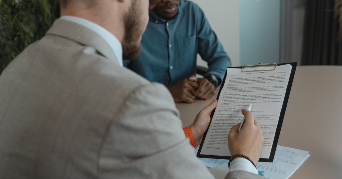 A recruiter reviews a candidate's documents during a job interview in a modern office setting.