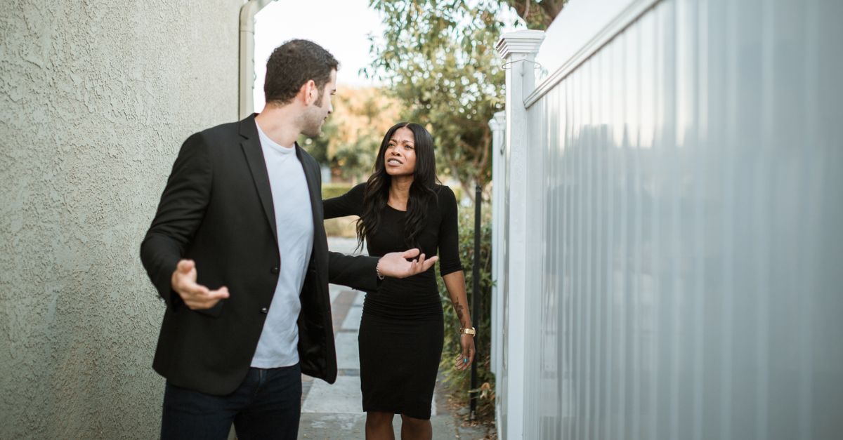 A couple arguing in an outdoor narrow passageway, showcasing relationship tension.