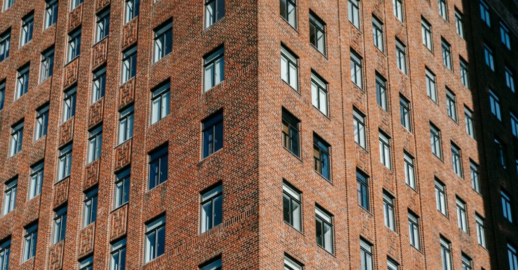 Low angle of exterior of contemporary apartment building with glass windows and red brick facade