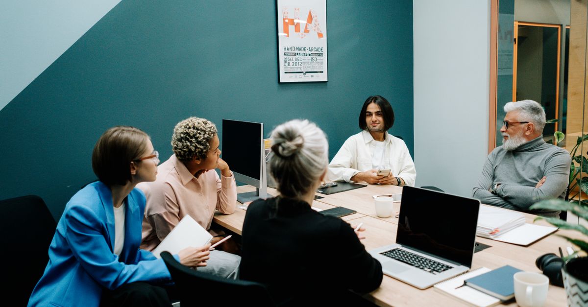 A diverse group of professionals engaged in a dynamic meeting in a modern office environment.