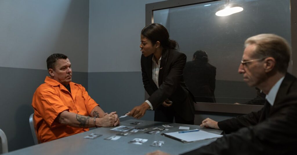 A tense interrogation scene with lawyers questioning an inmate in a prison setting.