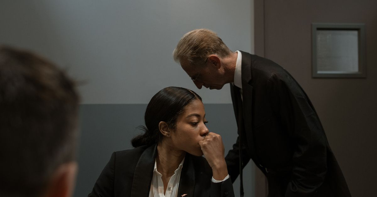 Detectives strategize during an interrogation in a prison room.