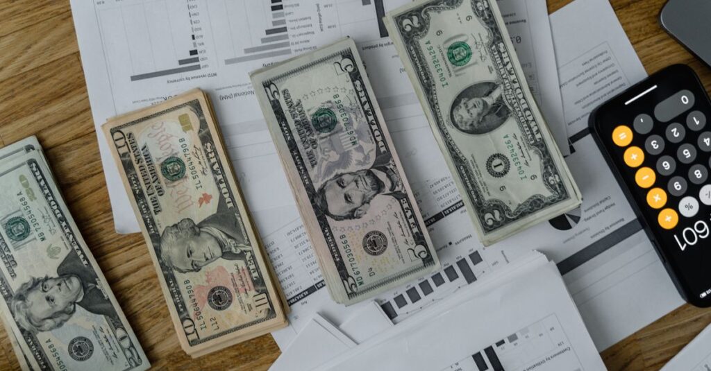 A workspace setup featuring cash, documents, and a calculator symbolizing financial analysis and budgeting.