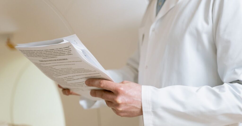 Doctor in a white coat examining medical papers in a healthcare setting.