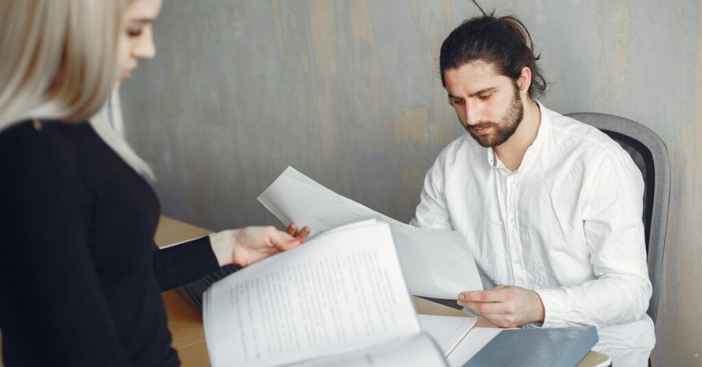 Two professionals reviewing important documents in a modern office setting.