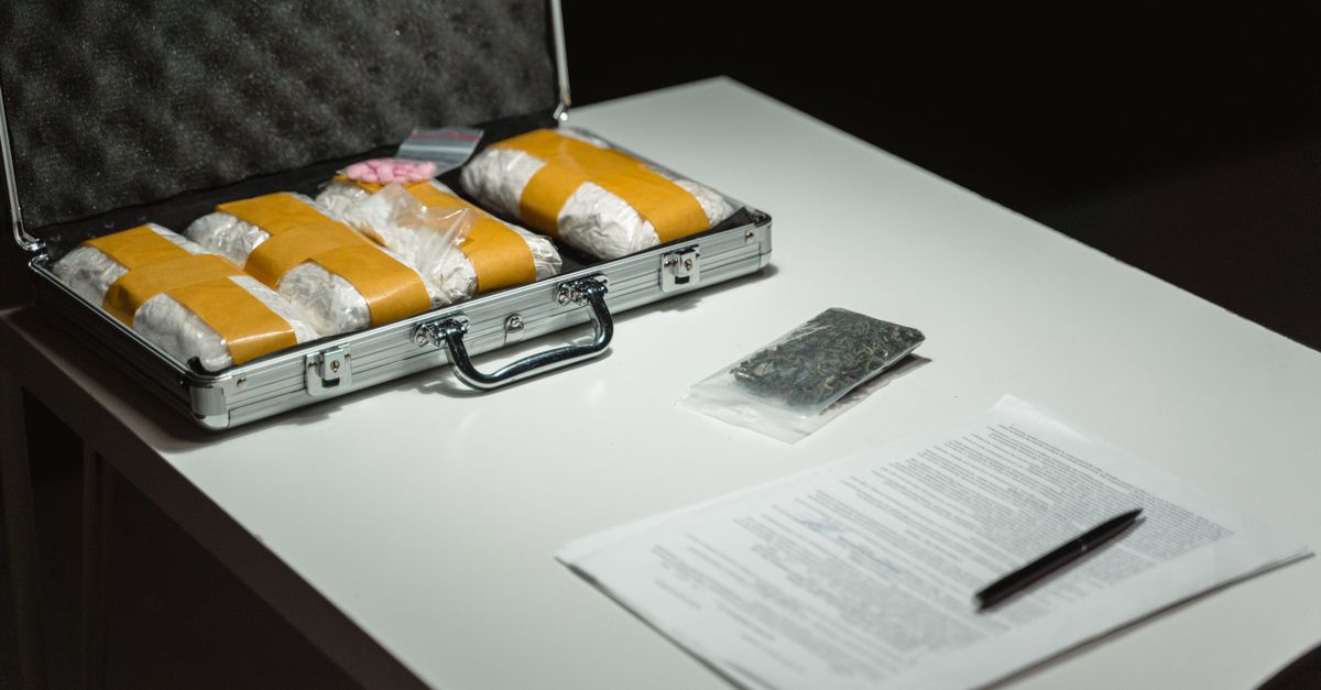 Briefcase with packages and documents on a table, suggesting illegal activity or crime scene investigation.