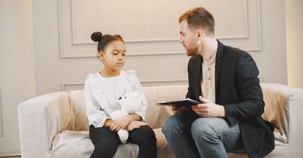 A young girl and a counselor having a therapy session indoors, fostering emotional support.