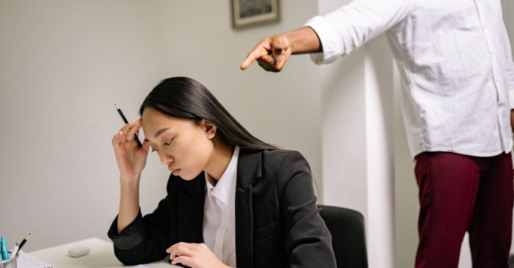An office scenario depicting a young woman experiencing bullying from a coworker.