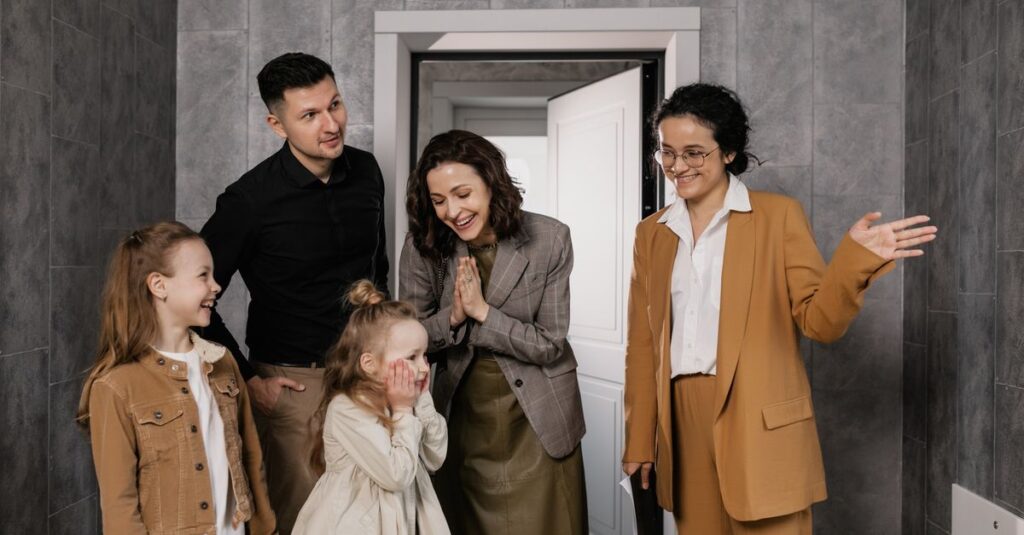 A joyful family is warmly welcomed by a realtor inside a modern home.