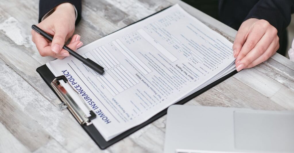 Close-up of hands reviewing a home insurance policy, emphasizing professionalism and finance.