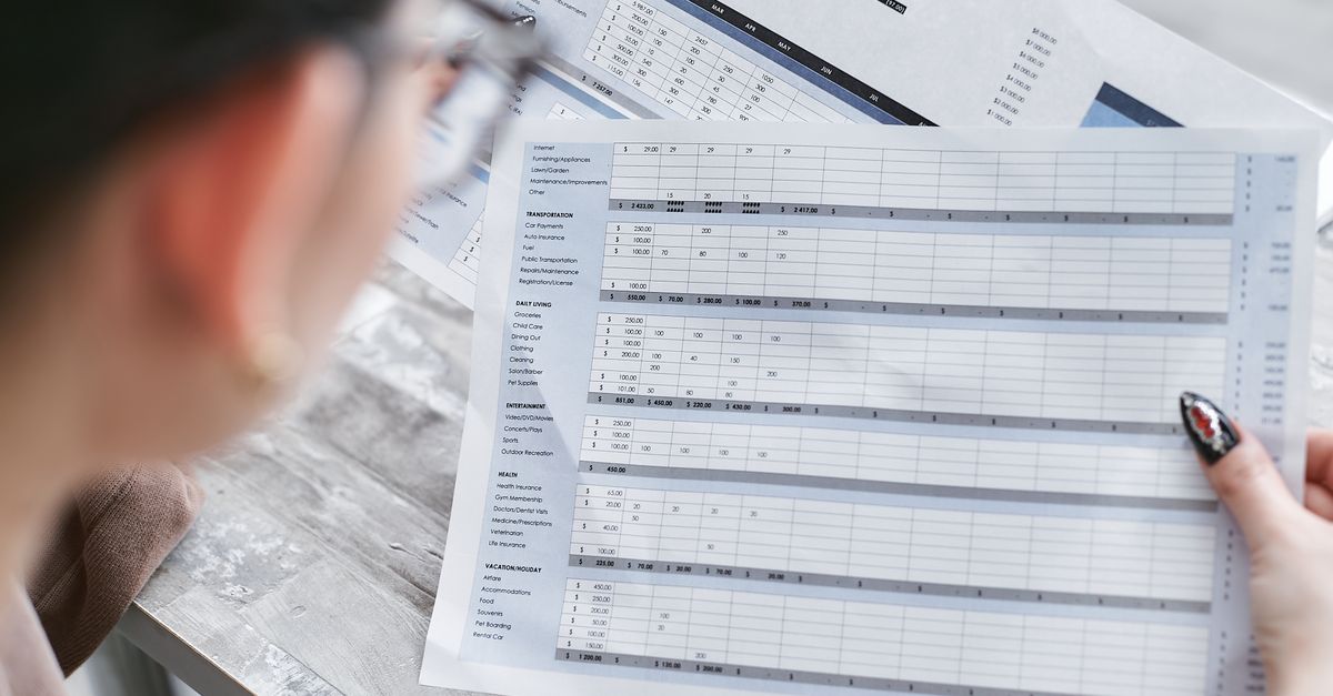 A businesswoman reviewing financial spreadsheets with charts and graphs in an office setting.
