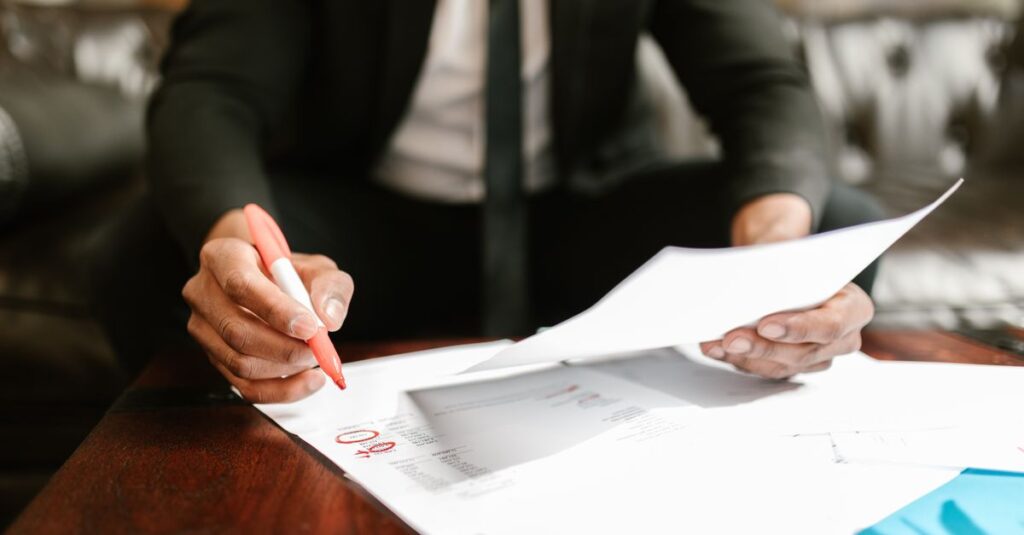 Businessman working with financial documents at office desk, highlighting details.