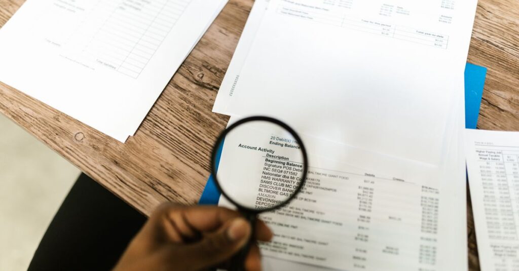 Close-up of hand using magnifying glass to review documents. Ideal for financial themes.