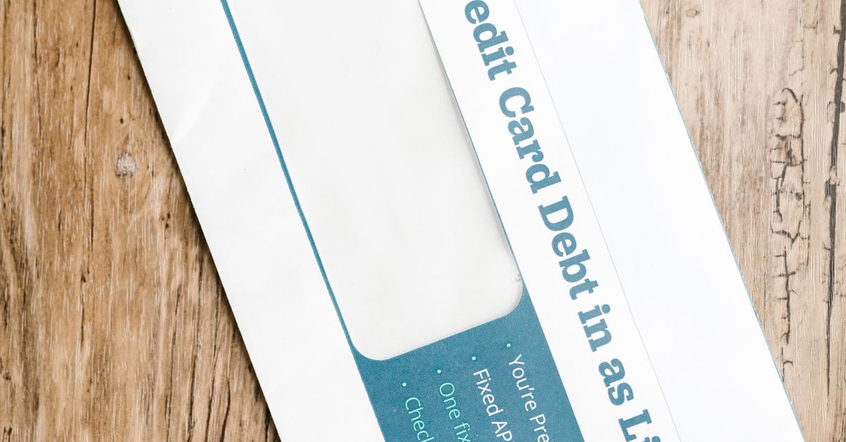 Close-up of a debt-related envelope on a wooden background, emphasizing financial concepts.