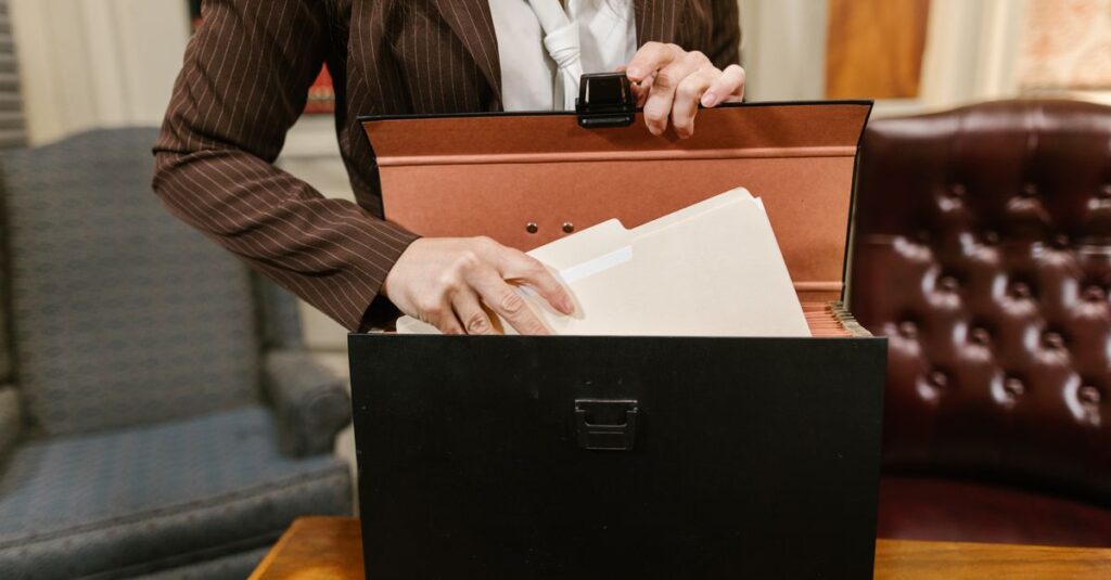 Close-up of a businesswoman organizing files in a black box in an office setting.