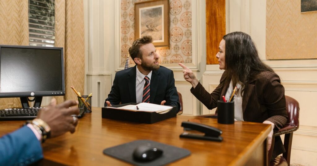 Professionals engaged in a serious discussion inside a law office with a computer on the desk.
