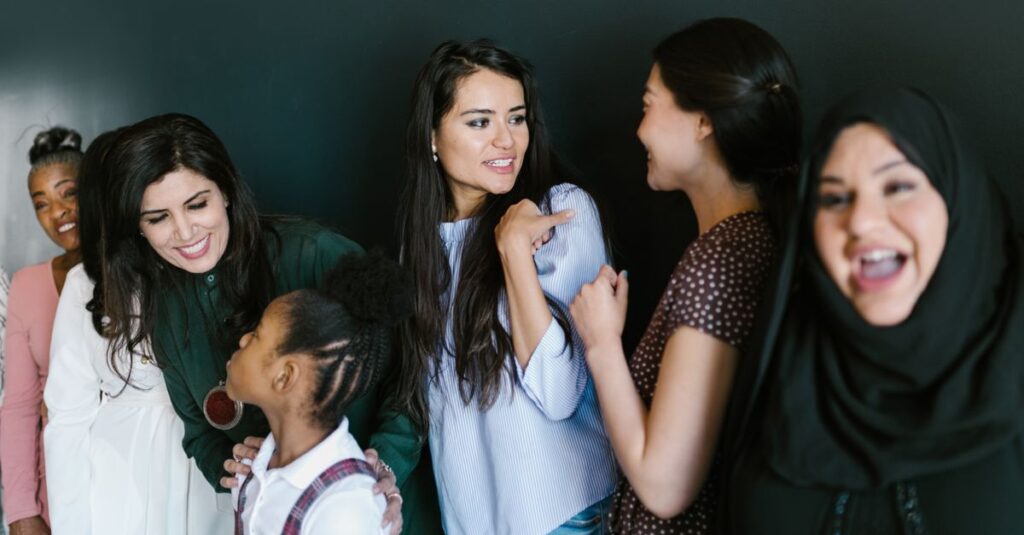 A diverse group of women and a child sharing a joyful moment indoors, showcasing friendship and empowerment.