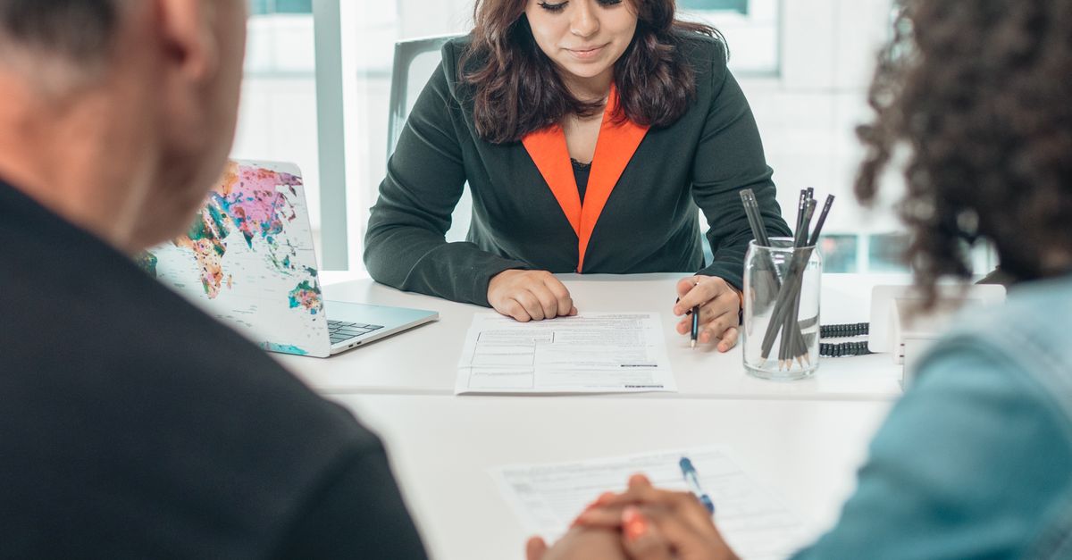A couple signing adoption papers in an office with a lawyer's assistance.