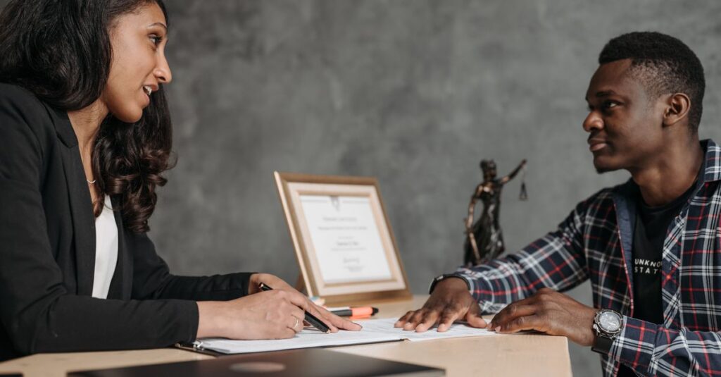 Two adults engaging in a professional conversation at an office desk, showcasing collaboration.