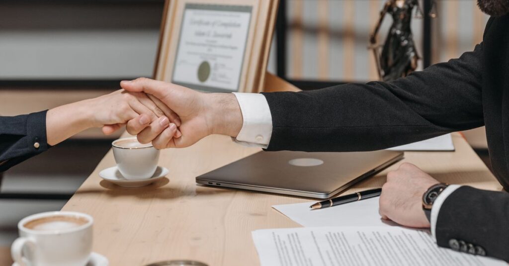 A formal handshake over a business contract in a corporate office setting.