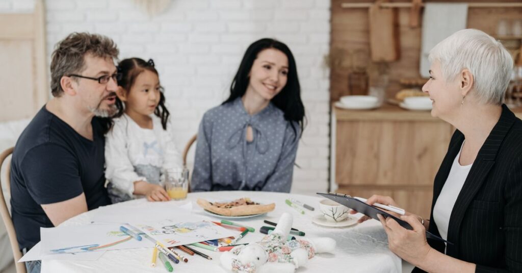 Adoptive family discussing with a social worker indoors, creating a warm, welcoming atmosphere.