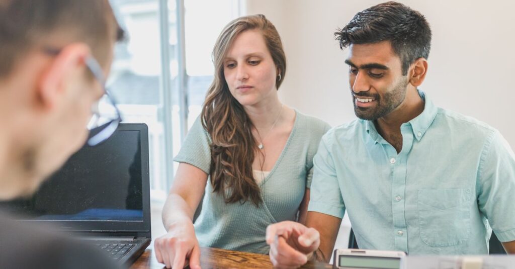 Young couple consulting with a financial advisor using a calculator and documents in a bright office setting.