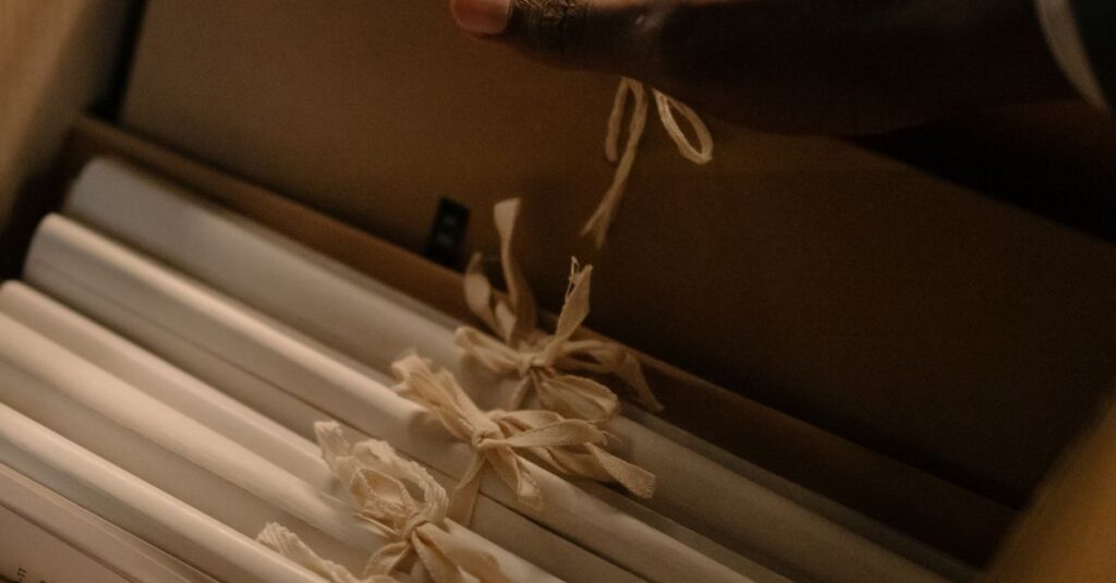 A hand reaches for tied documents inside an archive box, suggesting investigation or record keeping.