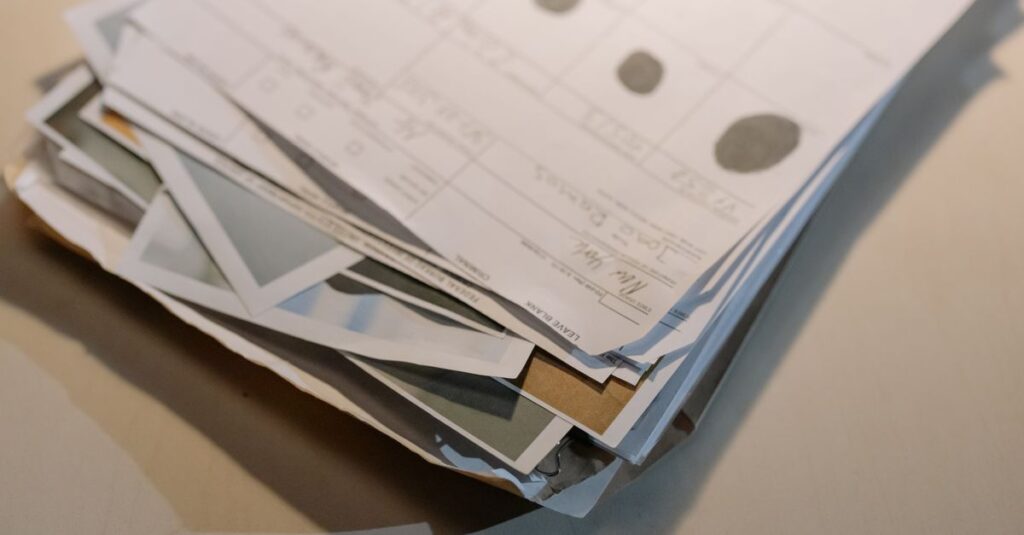 Close-up view of a stack of various papers and documents on a desk surface.