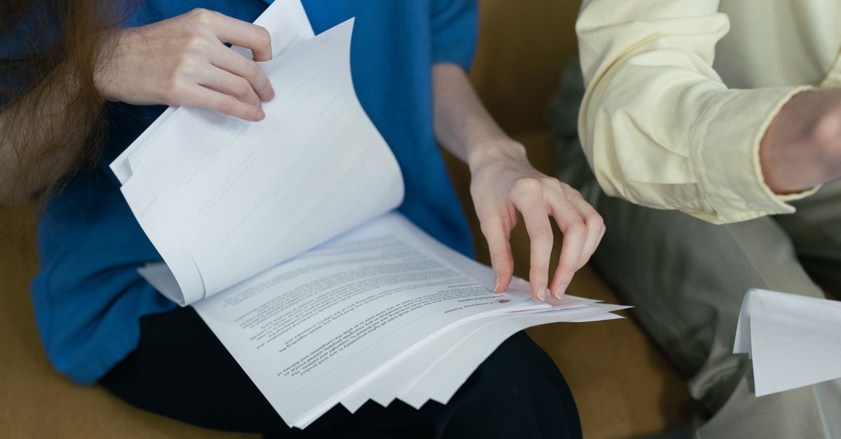 People in professional attire reviewing important documents together on a sofa.